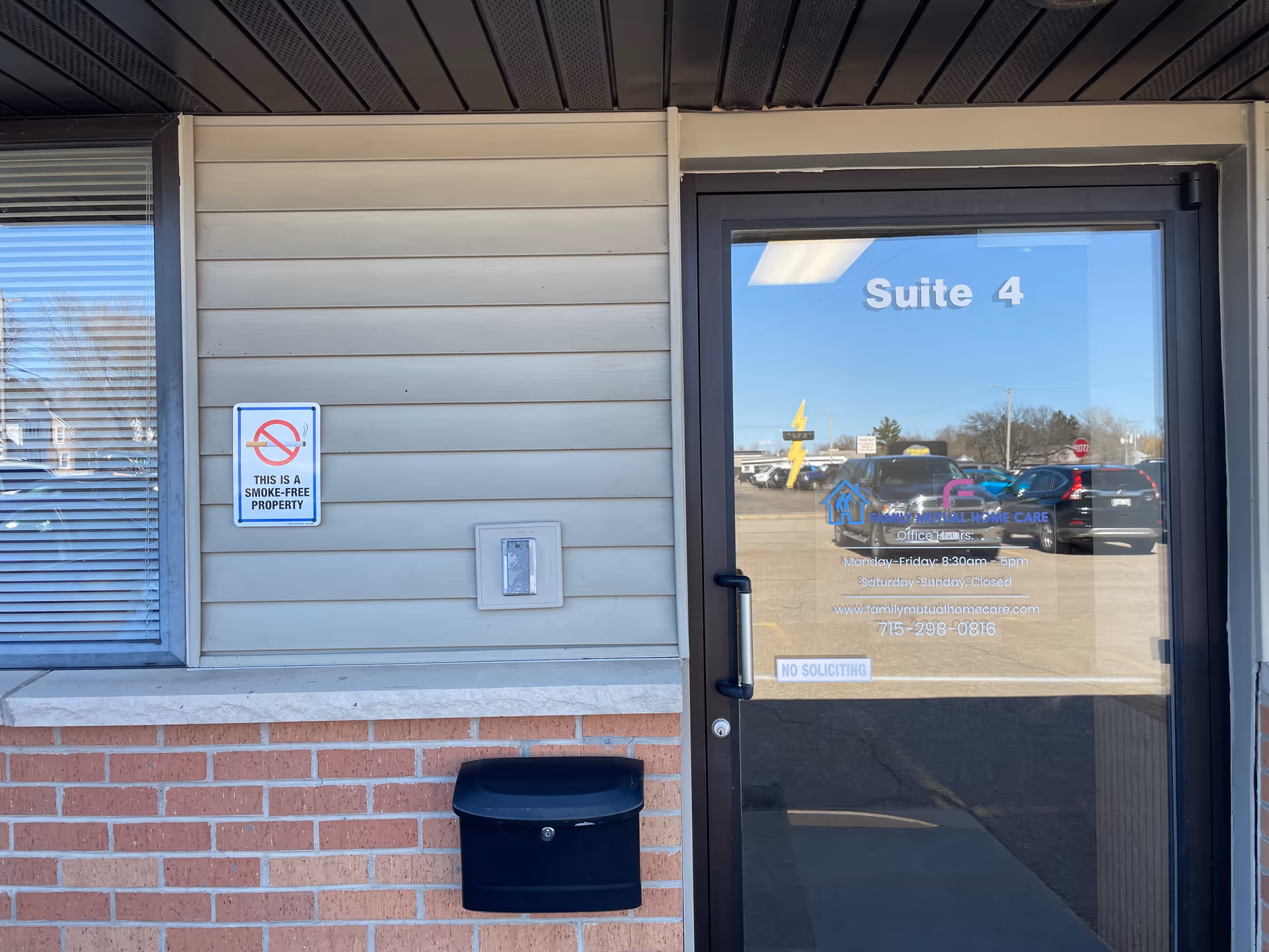 Exterior building entrance labeled Suite 4 with glass door and no-smoking sign
