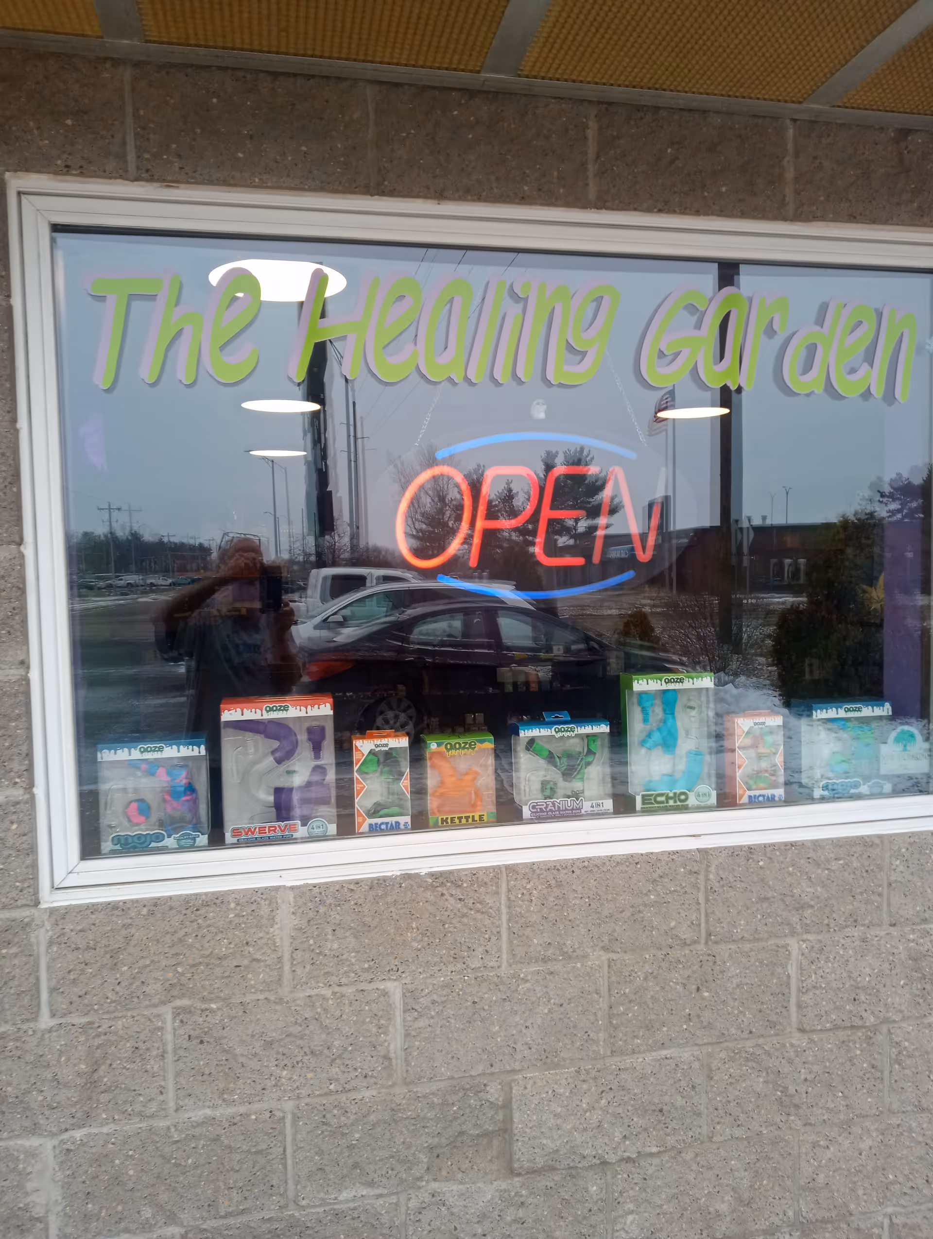 Storefront window of The Healing Garden with neon Open sign and product displays.