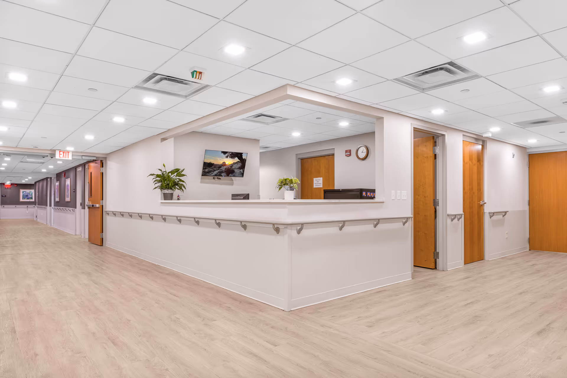 Bright interior hallway with a reception desk and wooden flooring.