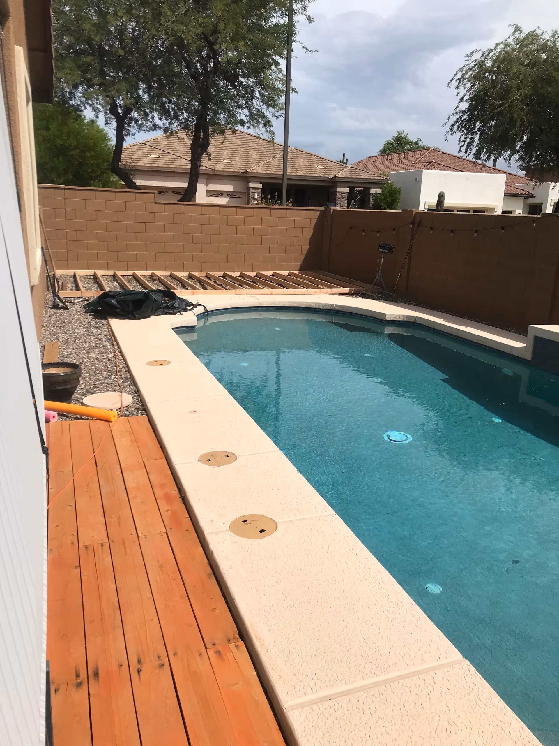 Outdoor pool area with wooden deck and privacy walls under construction.