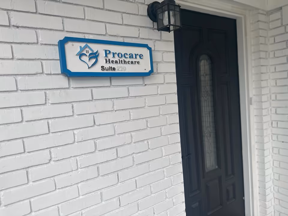 White brick exterior with a Procare Healthcare sign beside a dark front door.