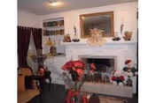 Cozy living room with a fireplace, festive decorations, red flowers, and seating.