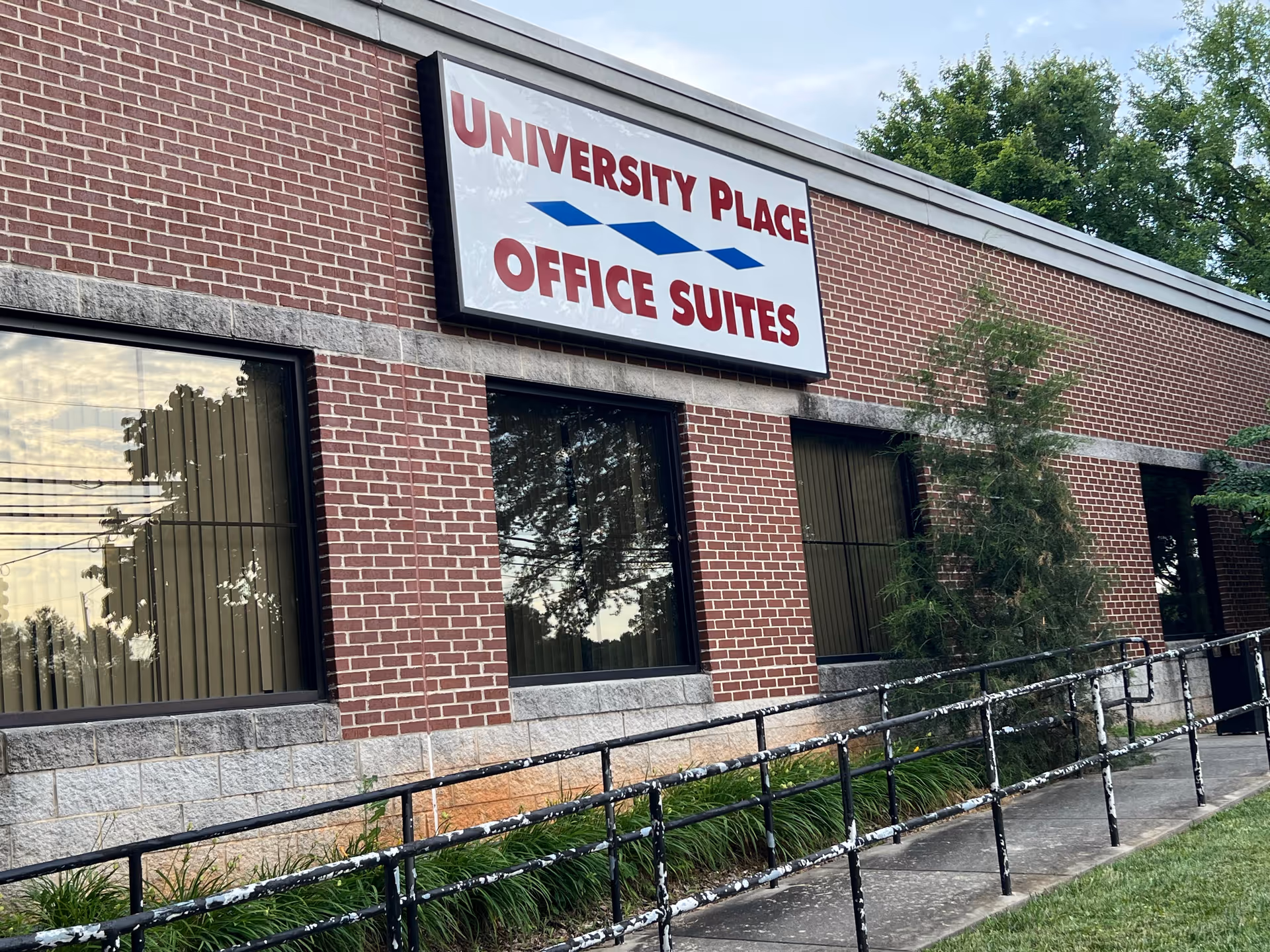 Brick building exterior with a large sign reading University Place Office Suites along a sidewalk.