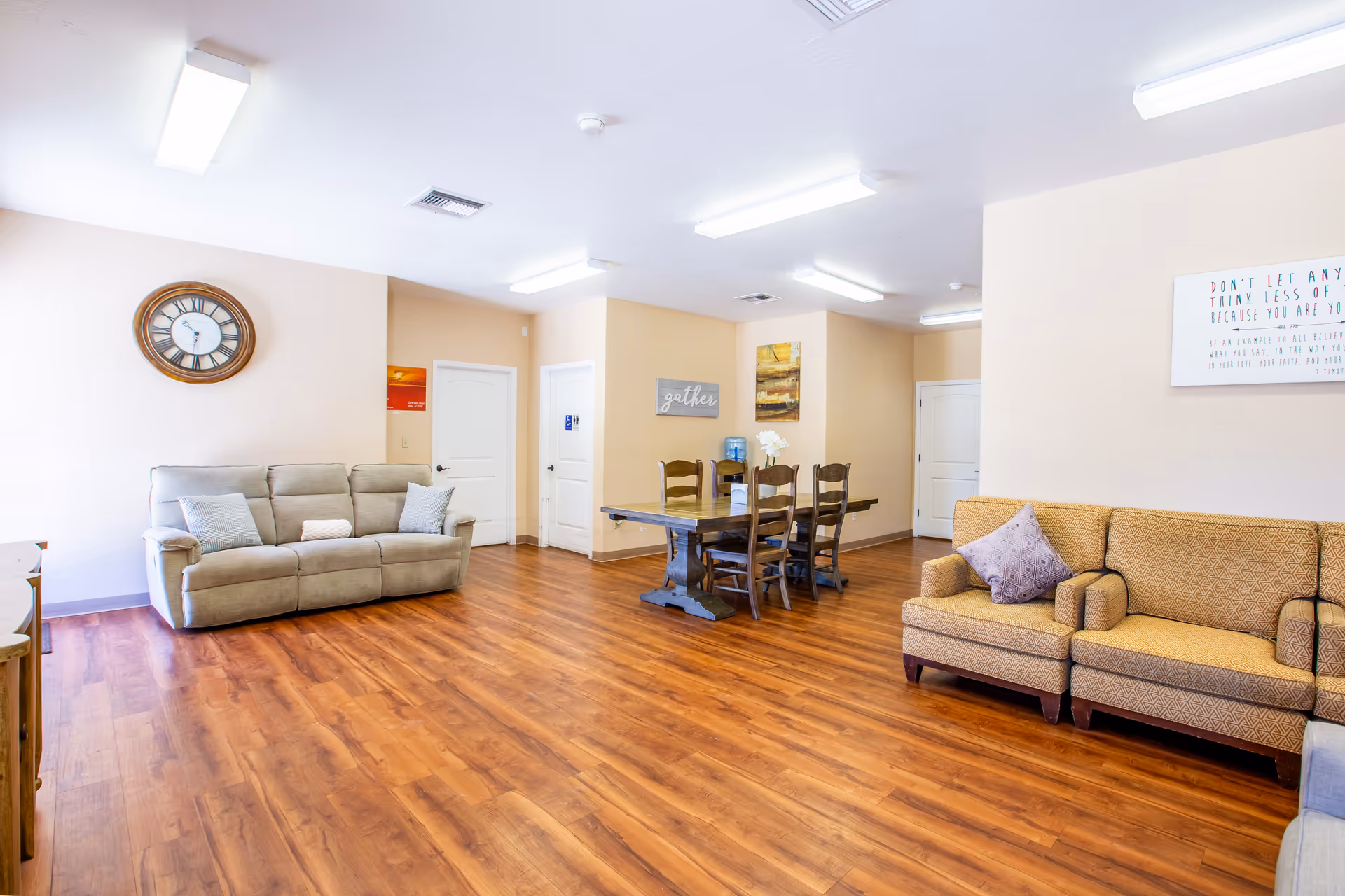 Bright interior living area with sofas, a dining table, and wood floors.
