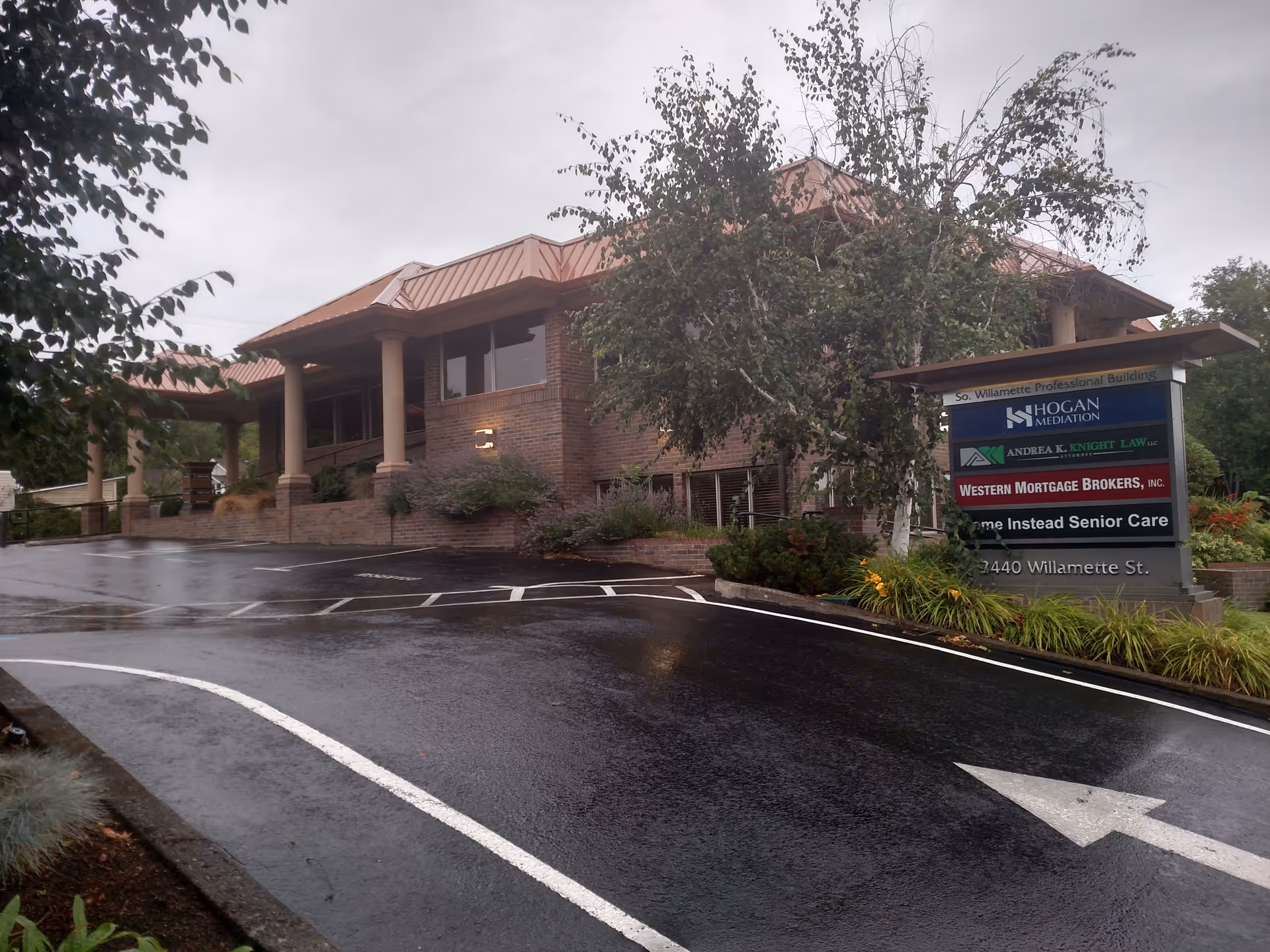 Exterior view of a brick building with Home Instead Senior Care sign on a rainy day.