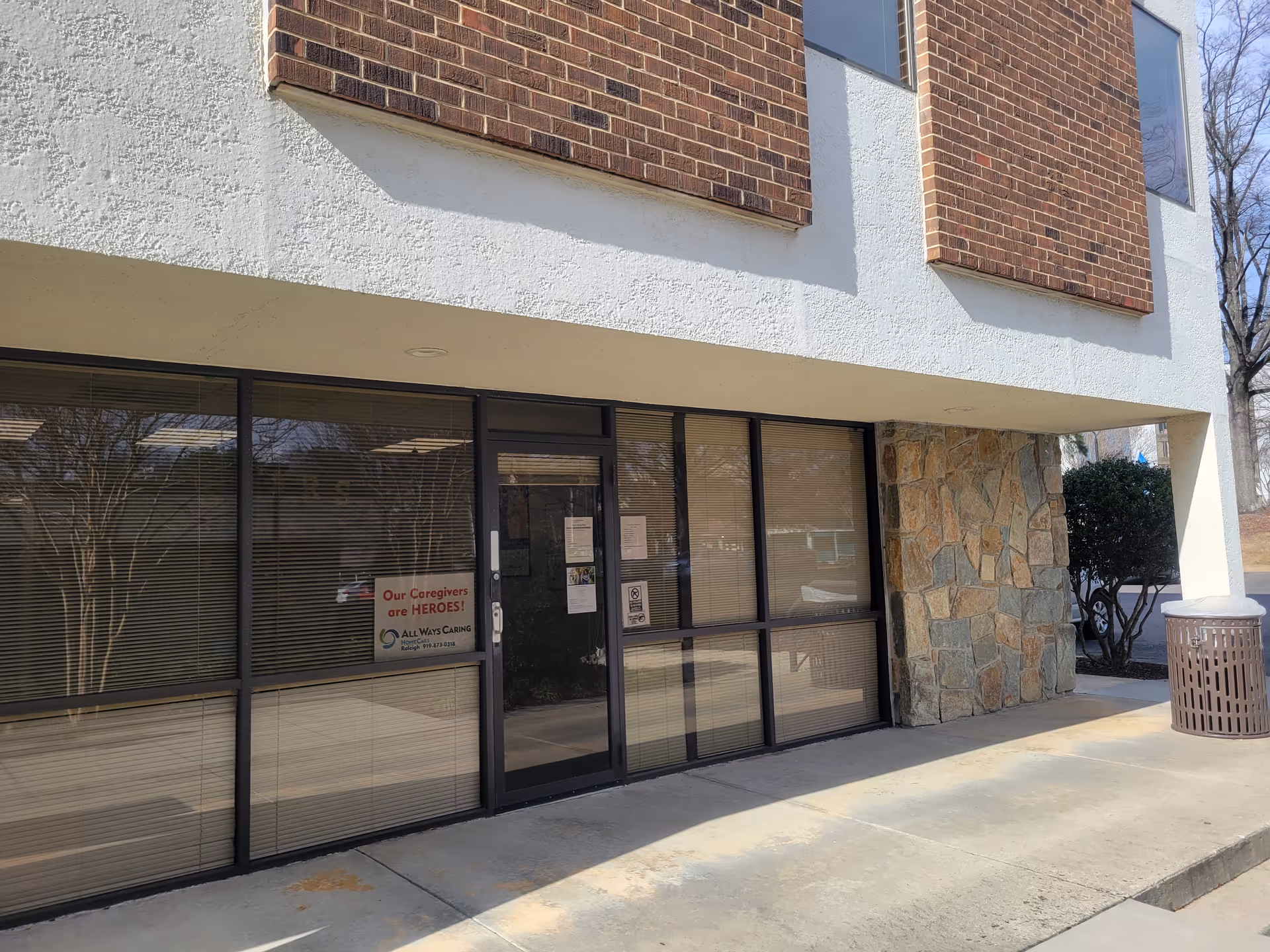 Exterior view of All Ways Caring HomeCare entrance with glass doors and brick facade.