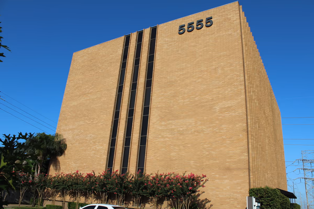 A tall brick building with vertical windows and the number 5555 on the facade