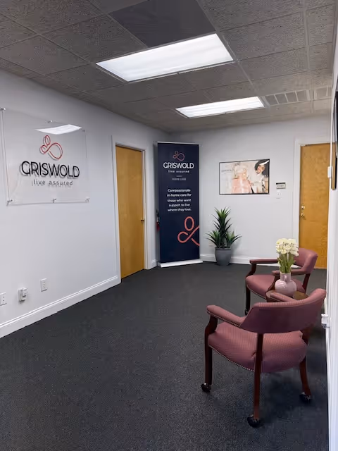 A waiting area with pink chairs, a potted plant, and Griswold banners in a hallway.