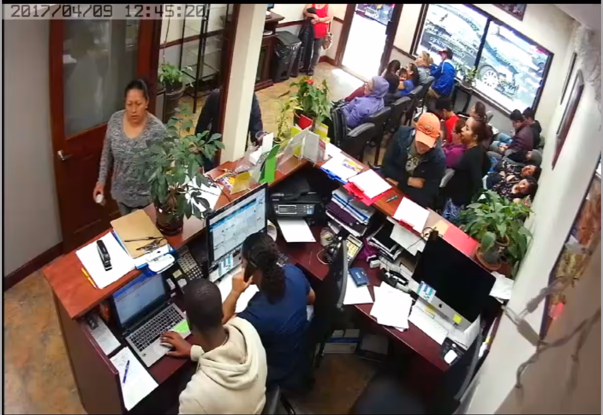 Busy reception area of a senior living facility with staff at desks and residents awaiting assistance.