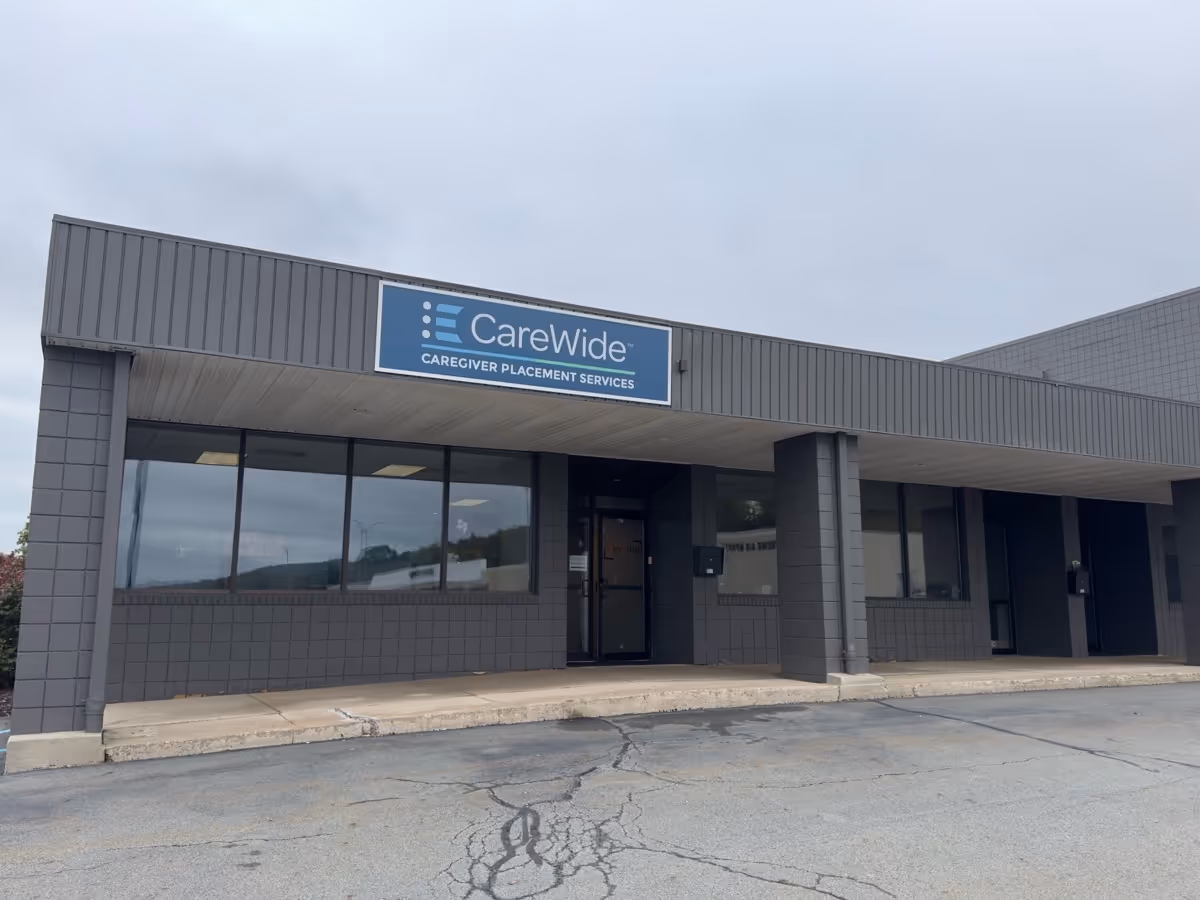 Grey commercial building with CareWide caregiver placement services sign on front facade.