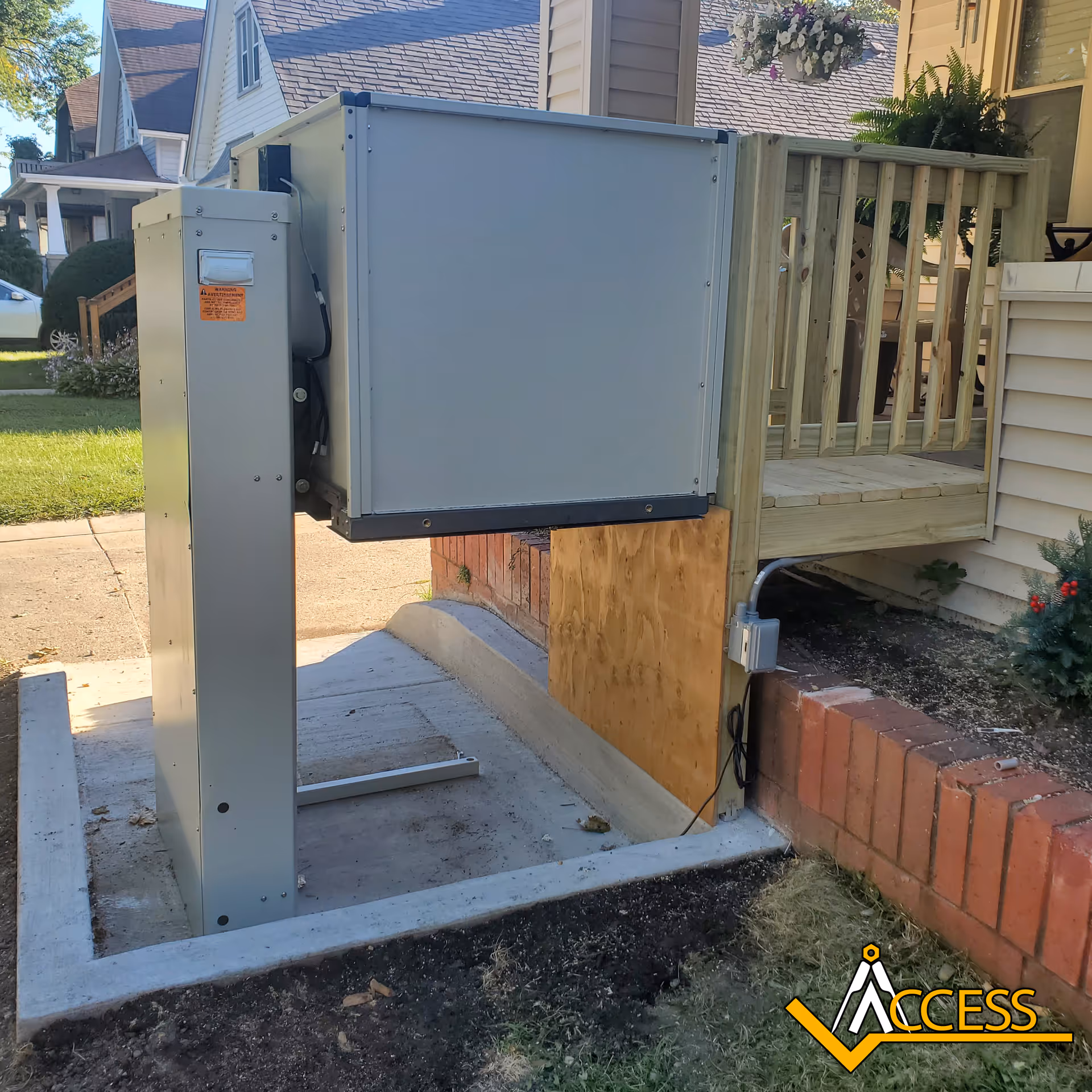 Outdoor accessibility elevator beside a house porch with railing.