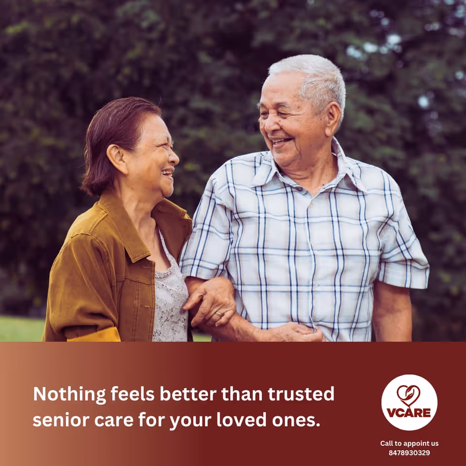 Two smiling seniors walk outdoors beside a VCARE banner and logo.