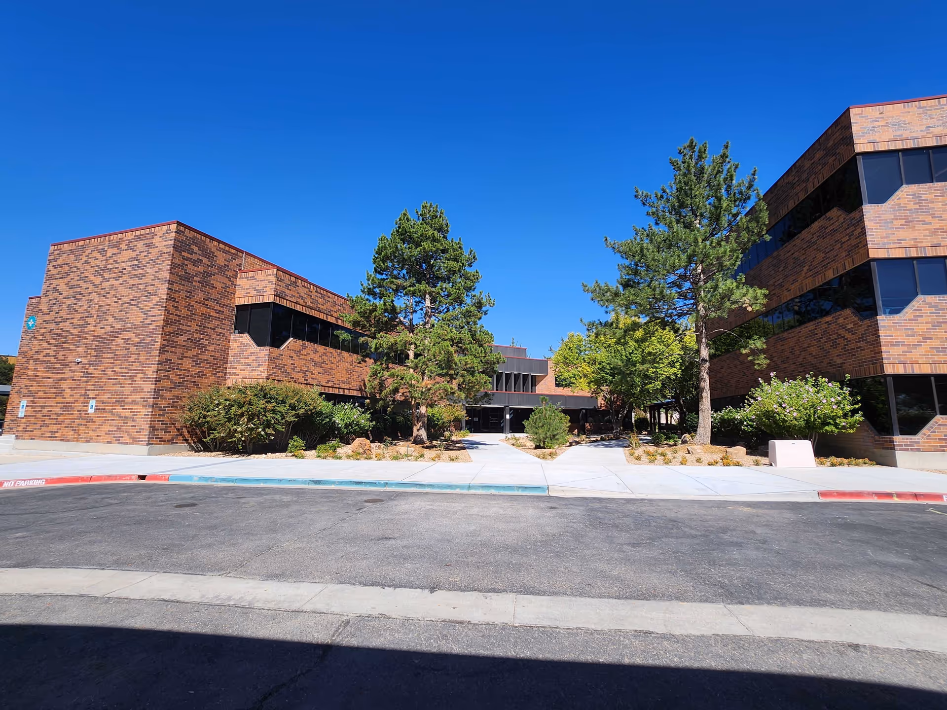 Exterior view of a brick senior living facility with trees and a driveway.