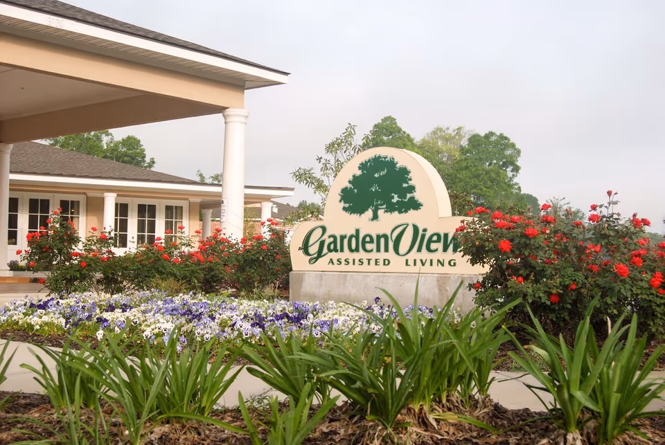 Entrance of Garden View Assisted Living with the facility sign amid flower beds and landscaping.