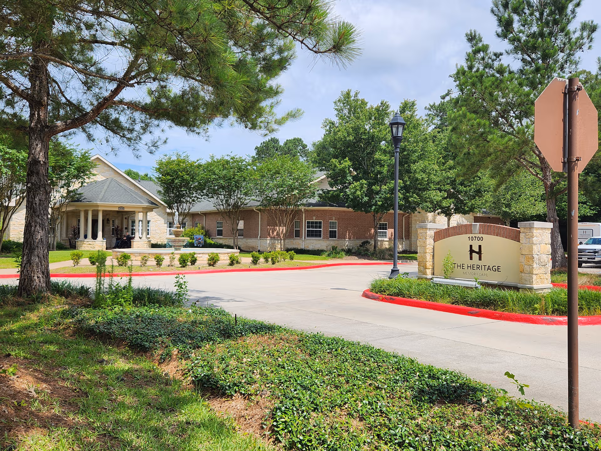 Exterior view of The Heritage Memory Care facility with landscaped entrance and front sign.