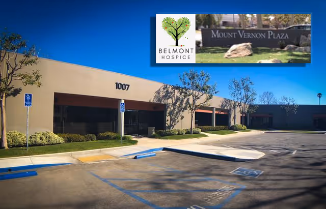 Exterior view of Belmont Hospice building with parking lot and blue sky.