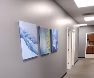 Gray hallway with three wall art canvases and a doorway to a kitchen area.