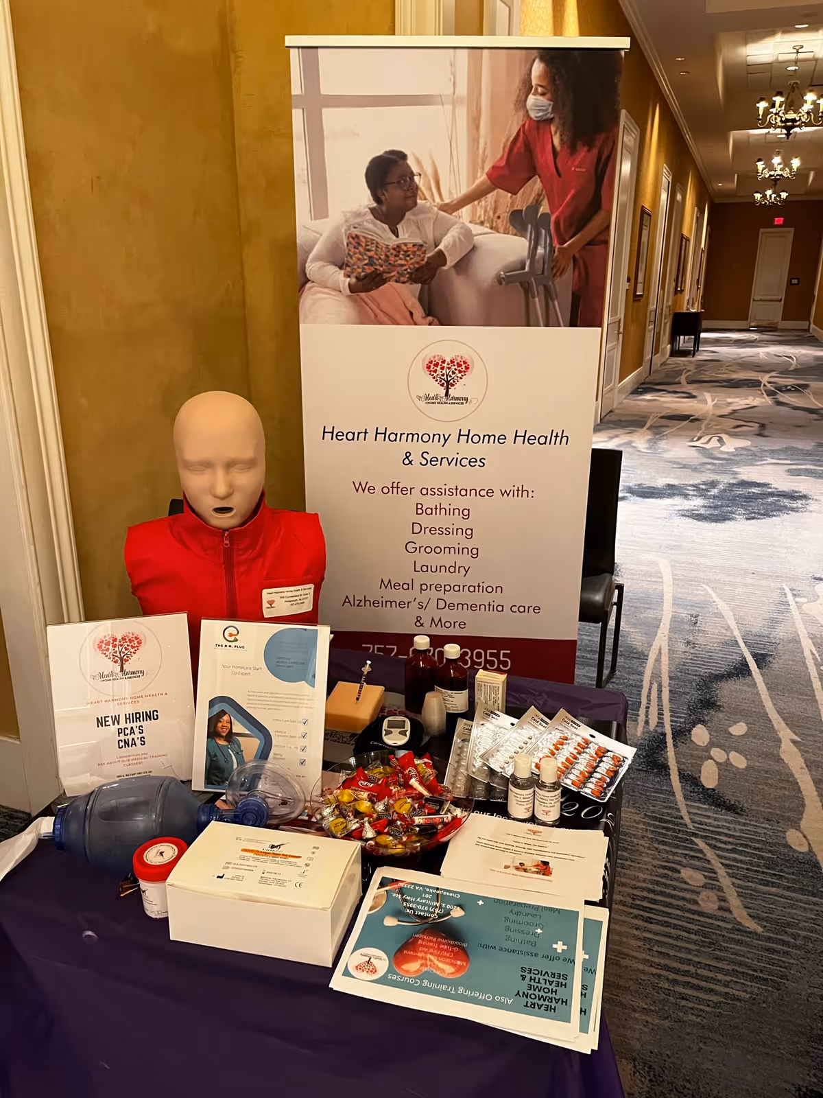 Indoor hallway setup featuring a Heart Harmony banner and promotional table with brochures.