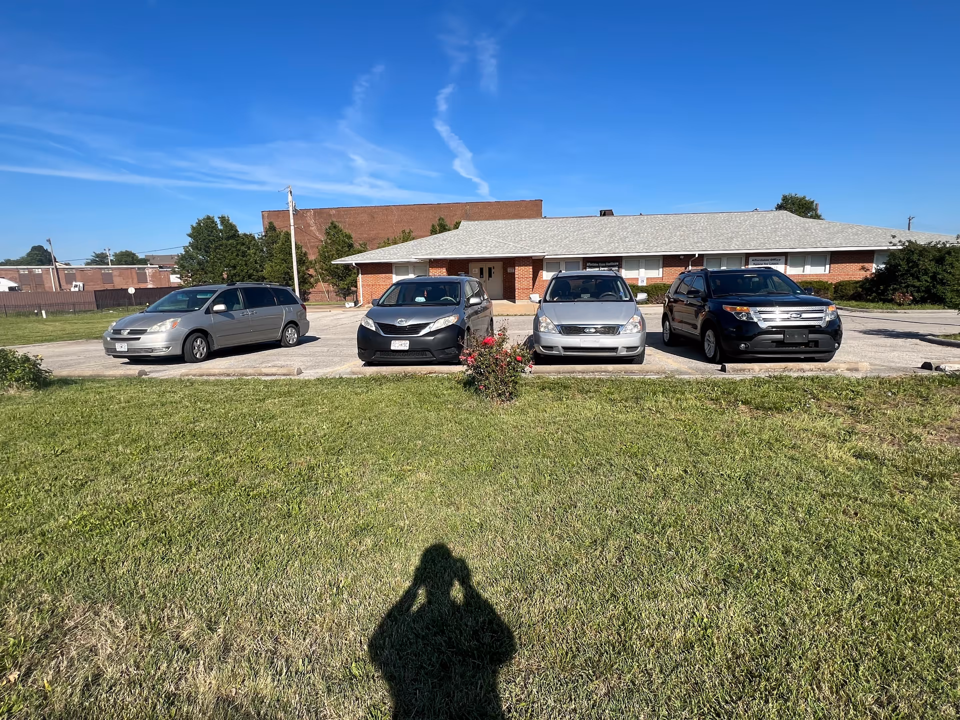 Front exterior of a single-story brick senior living facility with parked cars.