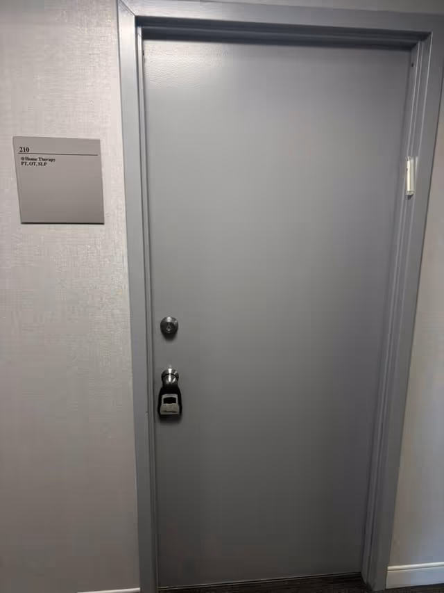 Gray hallway door with wall plaque reading Home Therapy PT, OT, SLP.