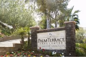 Stone entrance sign for Palm Terrace Care Center amid palm trees and landscaping.