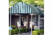 Exterior view of Locust Grove Retirement Village with a striped awning and brick facade.