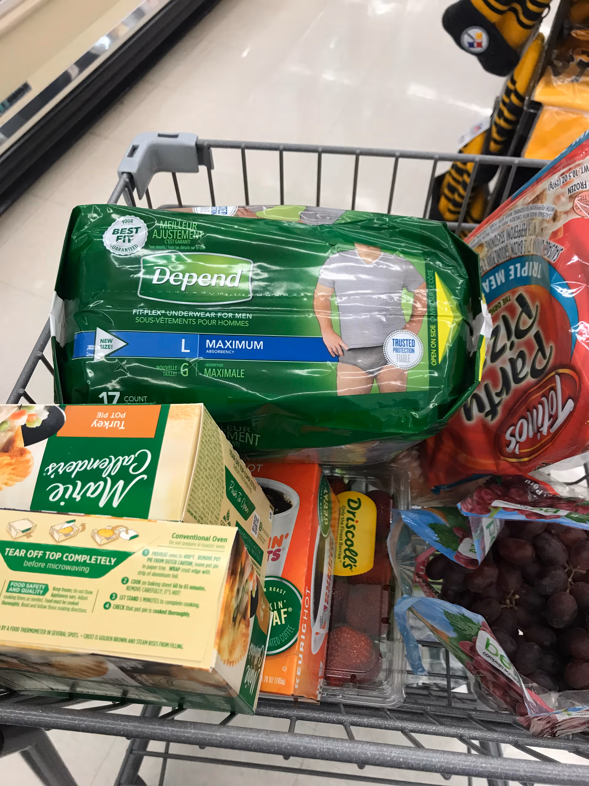 Shopping cart filled with assorted groceries in a supermarket aisle