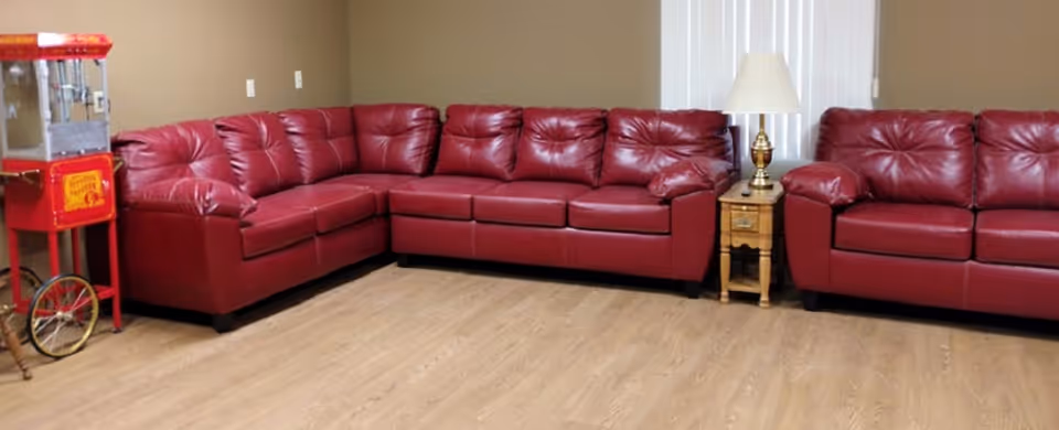 Red leather sectional sofas fill a spacious living room lounge with a lamp.