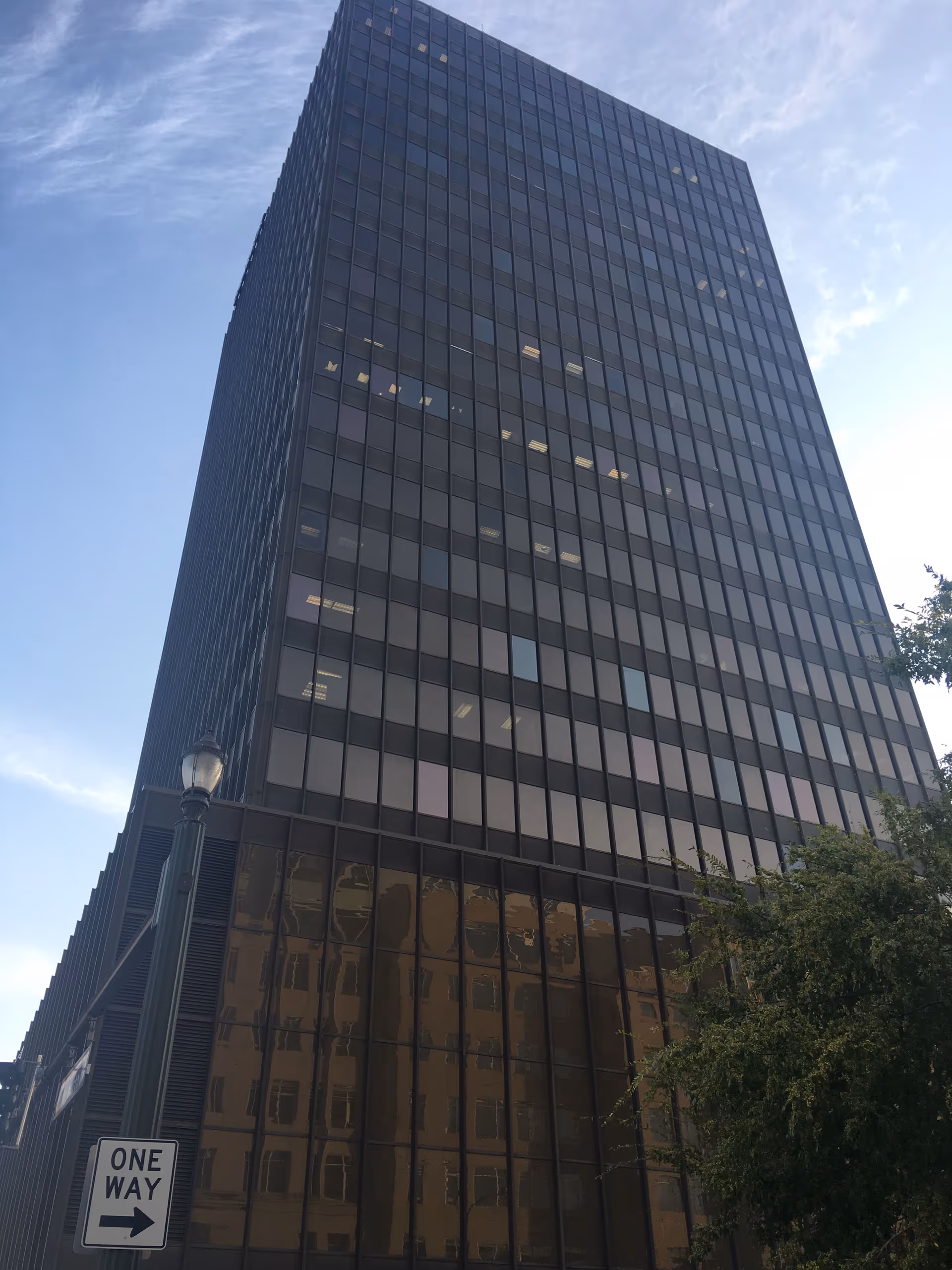 Tall glass office building with reflective windows under blue sky.
