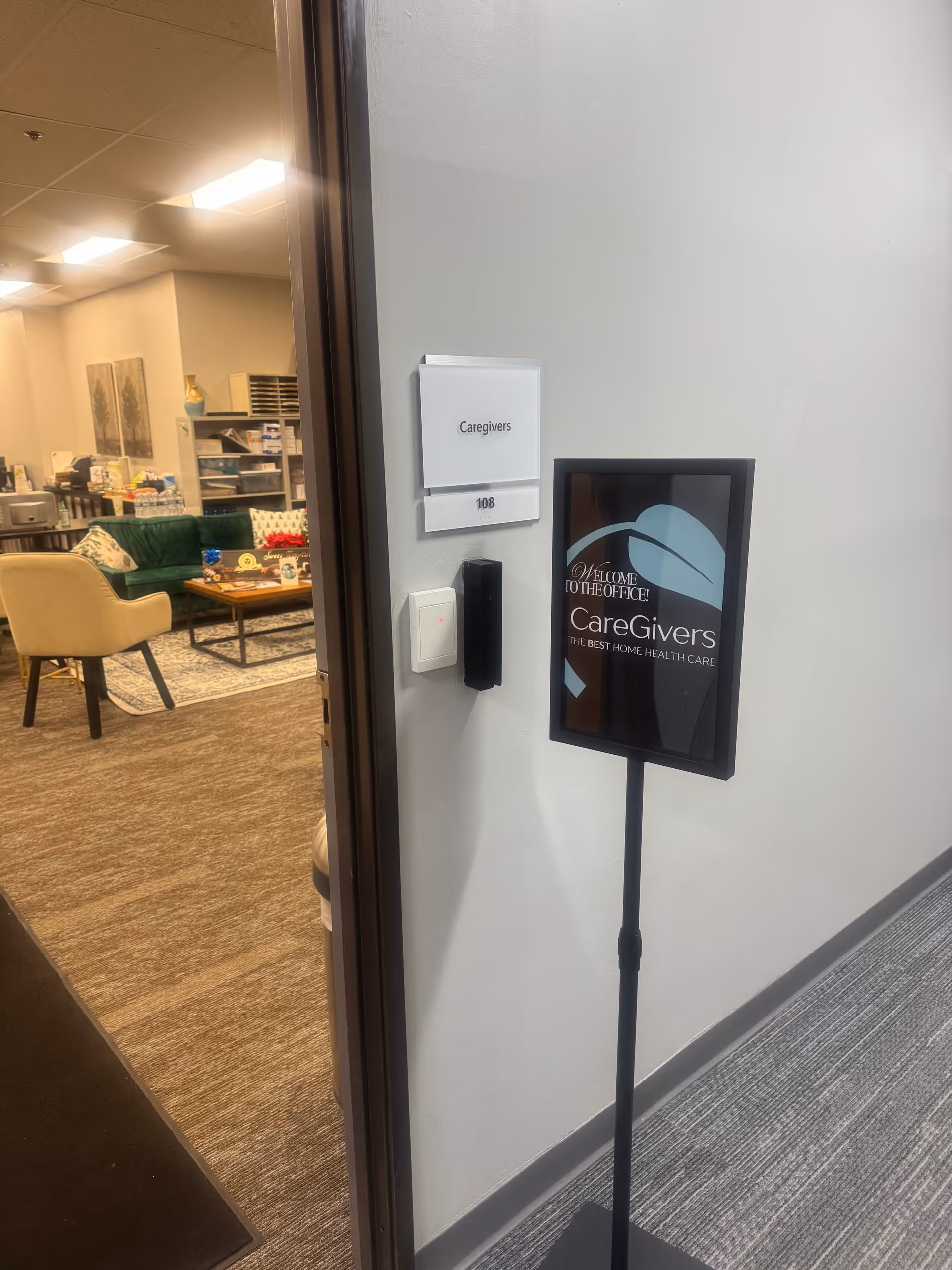 Entrance to a lounge with beige chairs and a freestanding Caregivers sign.