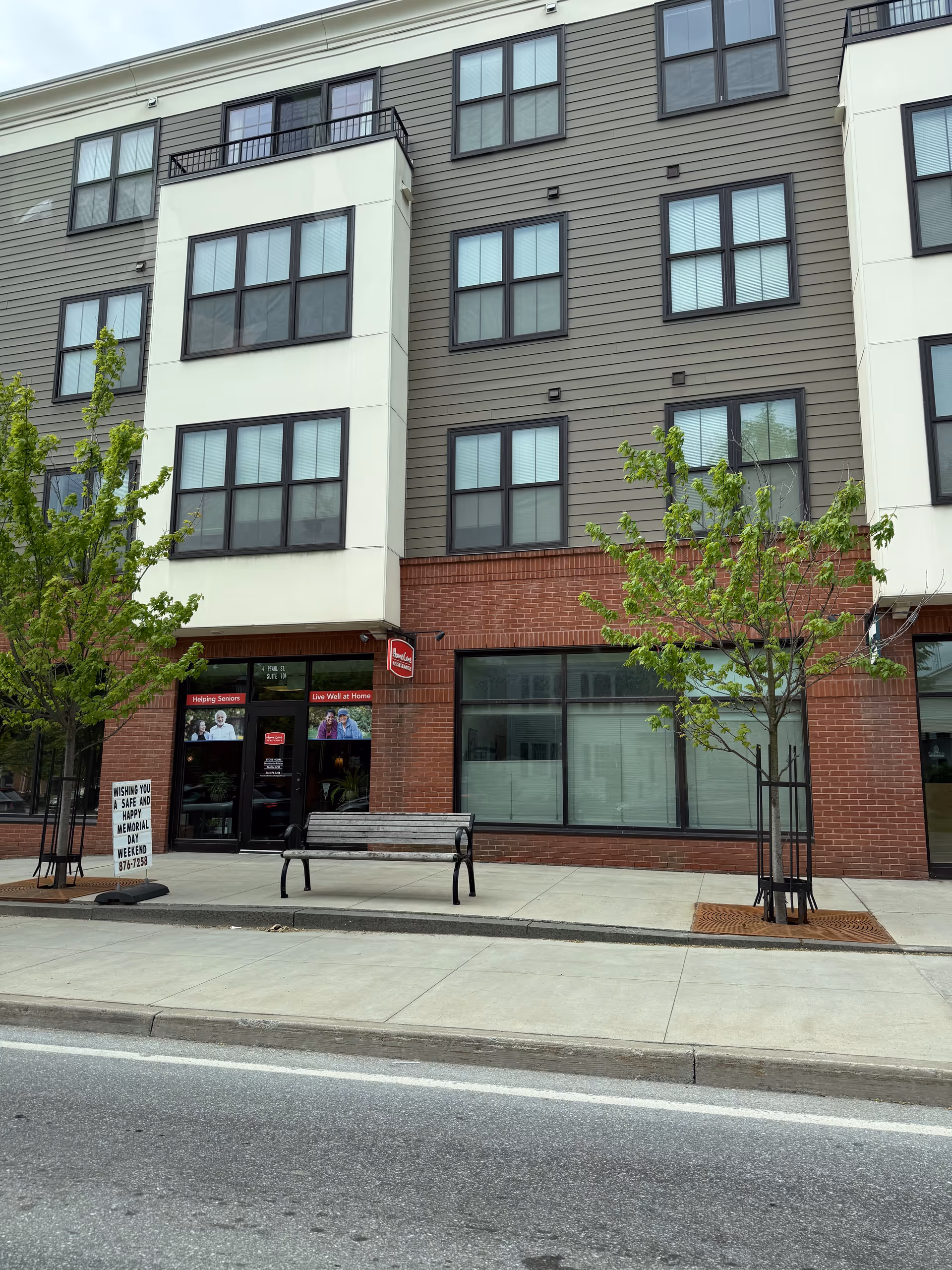 Exterior of a modern multi-story building with a storefront and bench.