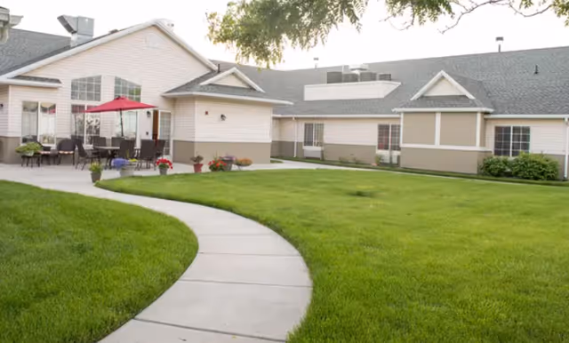 Exterior view of The Gables Assisted Living of Brigham City with a curved walkway and patio.
