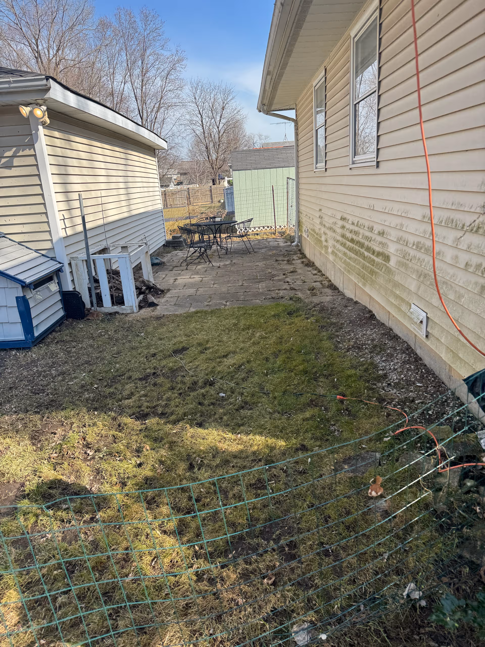 Outdoor patio beside beige building with table, chairs, and fenced yard.