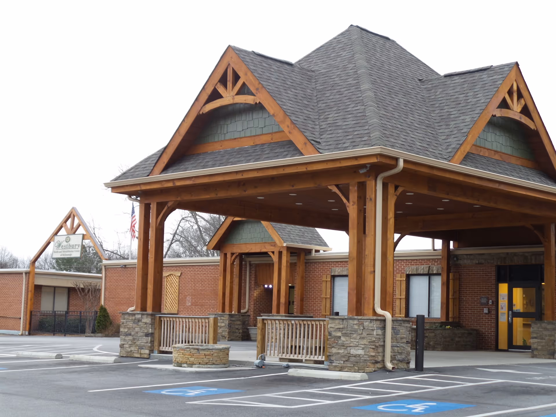 Wooden entrance canopy over brick facility with parking at Westbury Mcdonough.