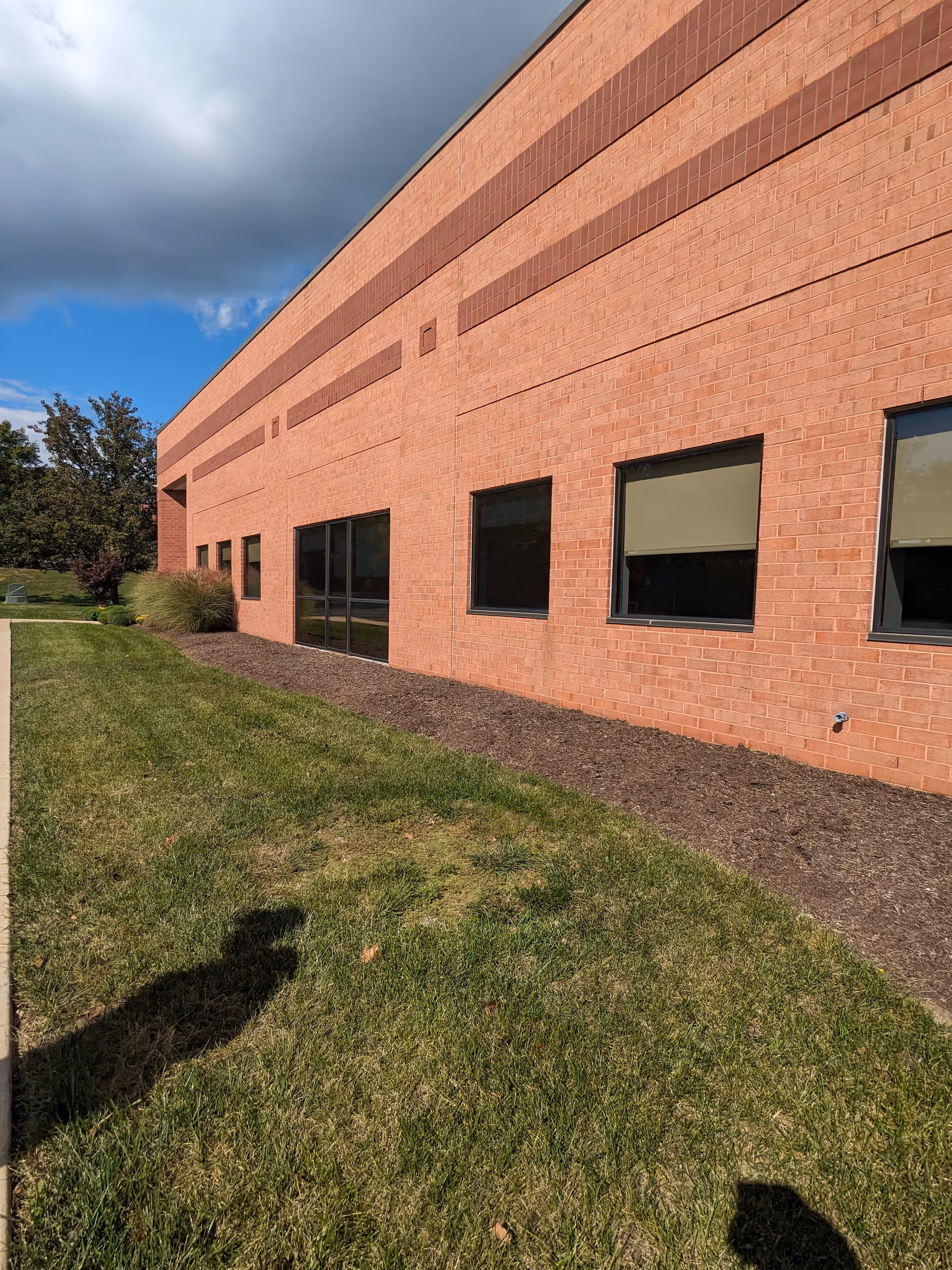Exterior brick building of Pentec Health with windows and a green lawn.