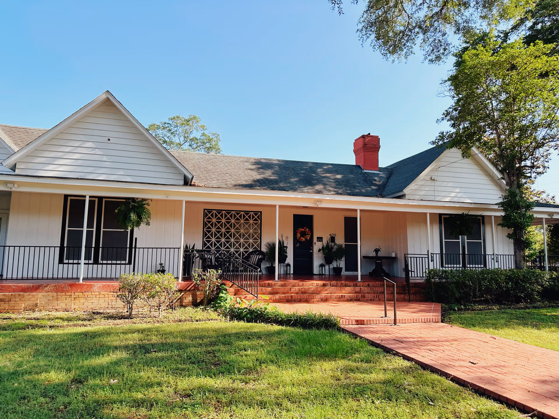 Single-story assisted living residence with front porch, white siding, and brick steps.