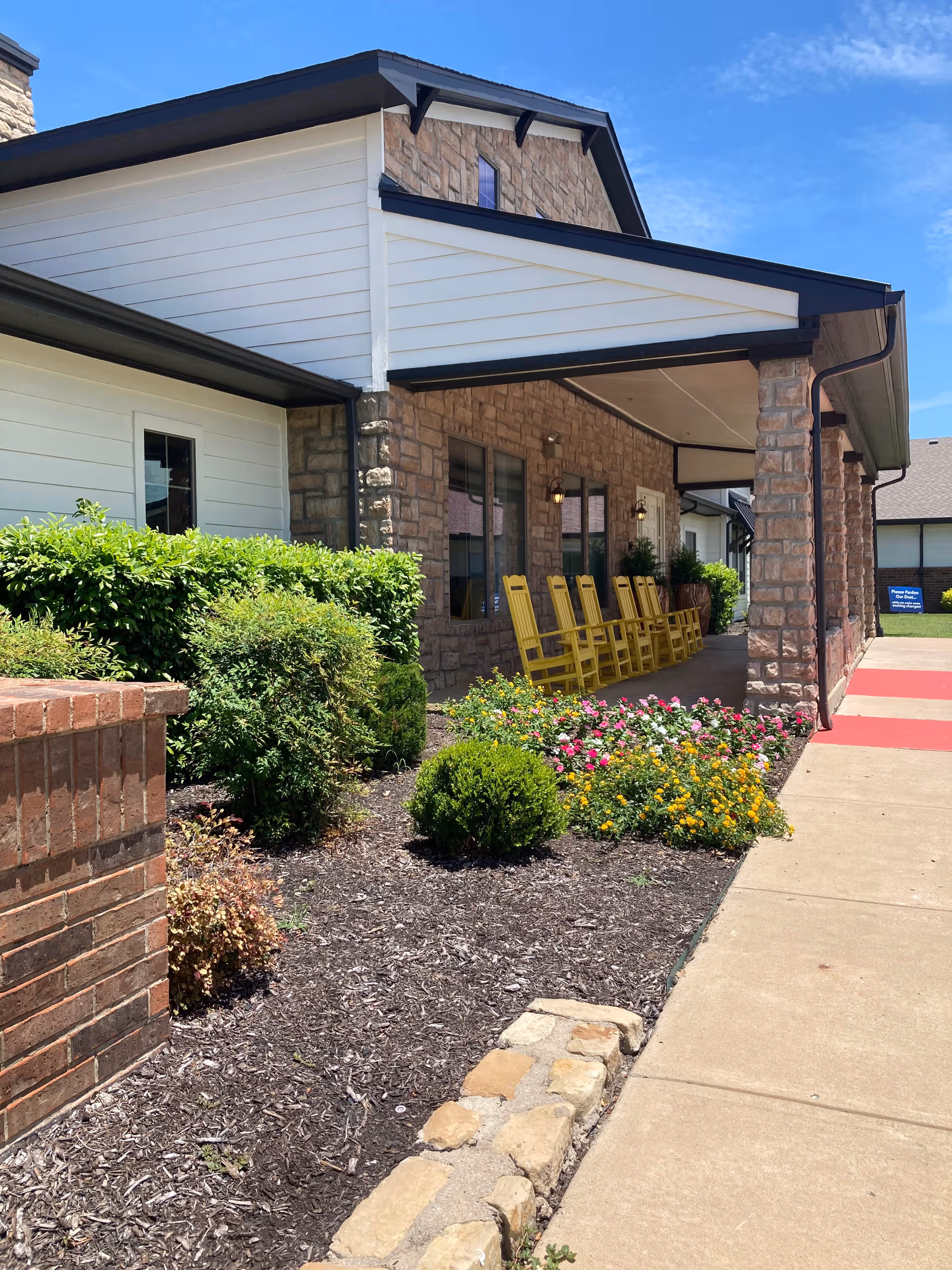 Exterior view of Walnut Creek Assisted Living entrance with stone facade and yellow chairs.