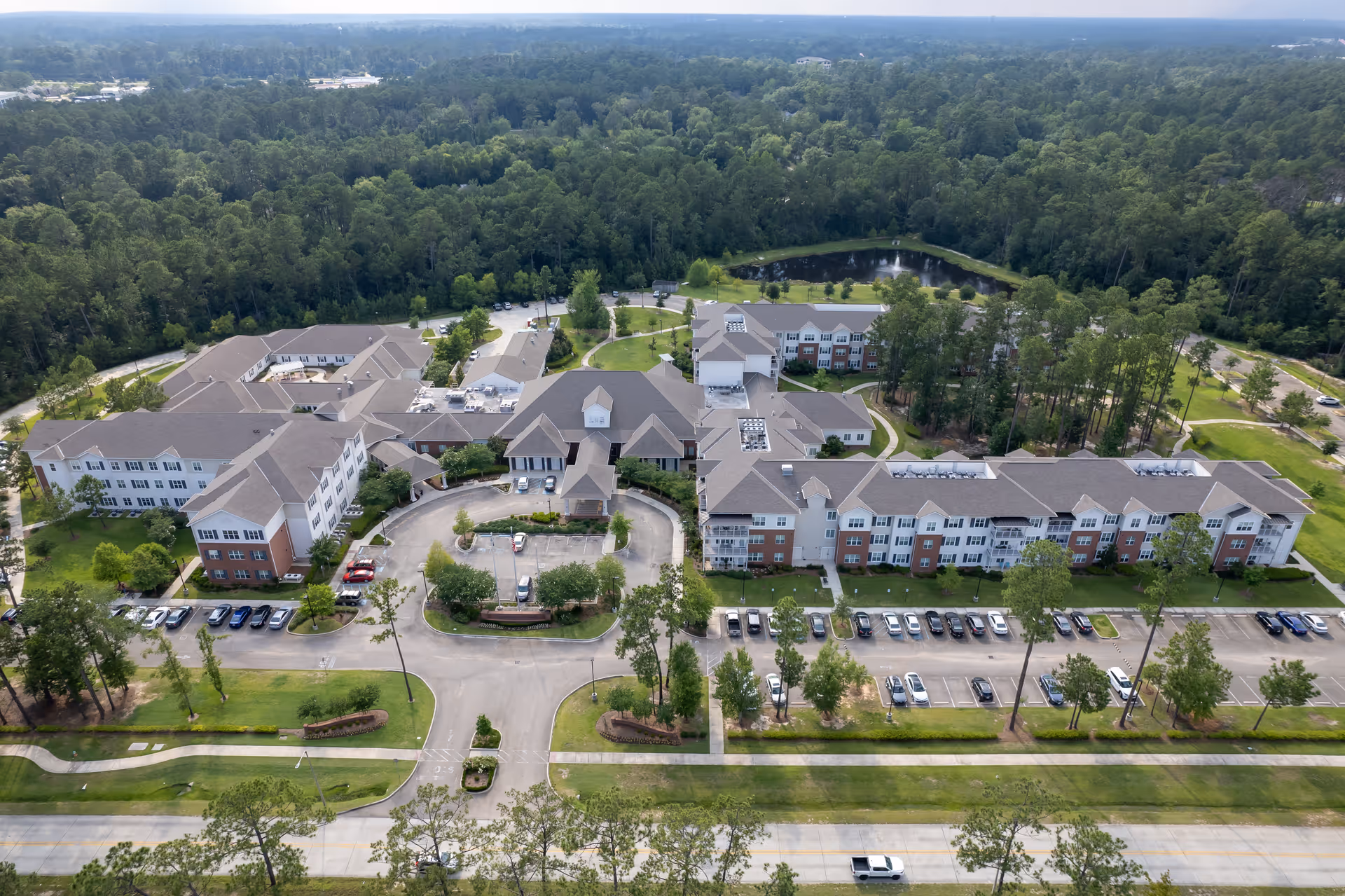 Aerial view of St. Anthony's Gardens senior living campus with multiple connected buildings, parking areas, and surrounding trees.