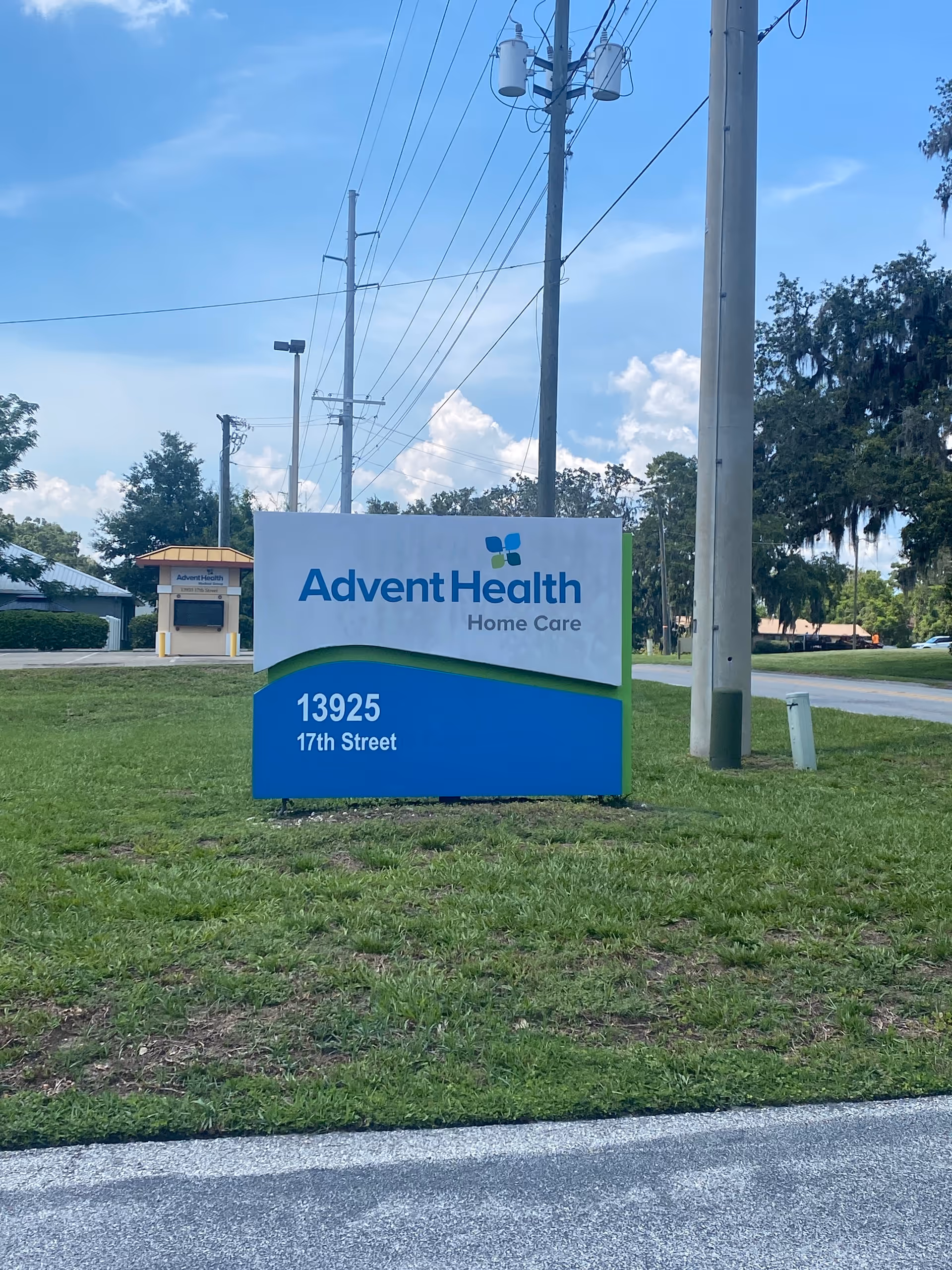A large AdventHealth Home Care sign sits on a grassy median by the street.