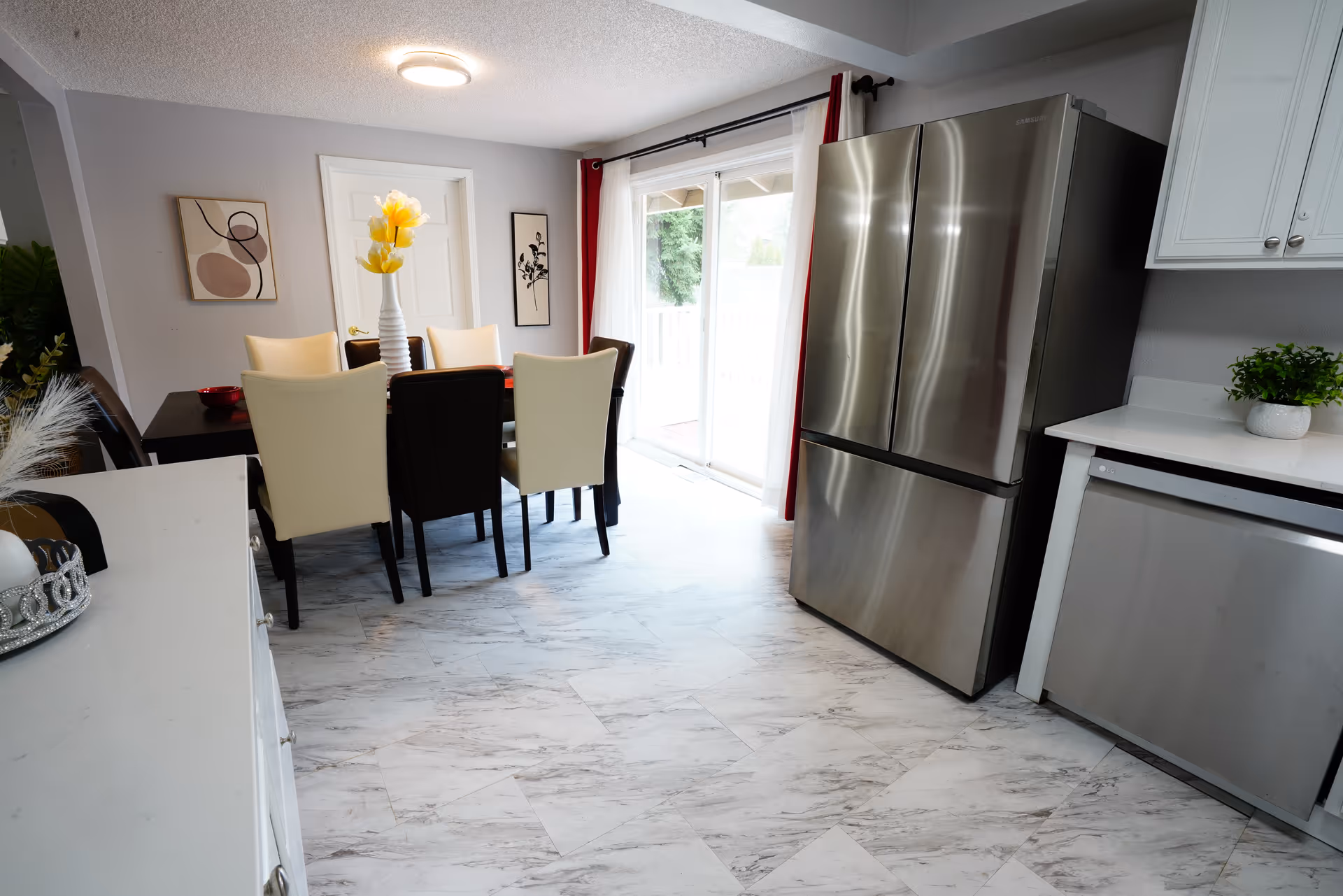 Dining room with a dark table, cream chairs, stainless fridge, and sliding glass door.