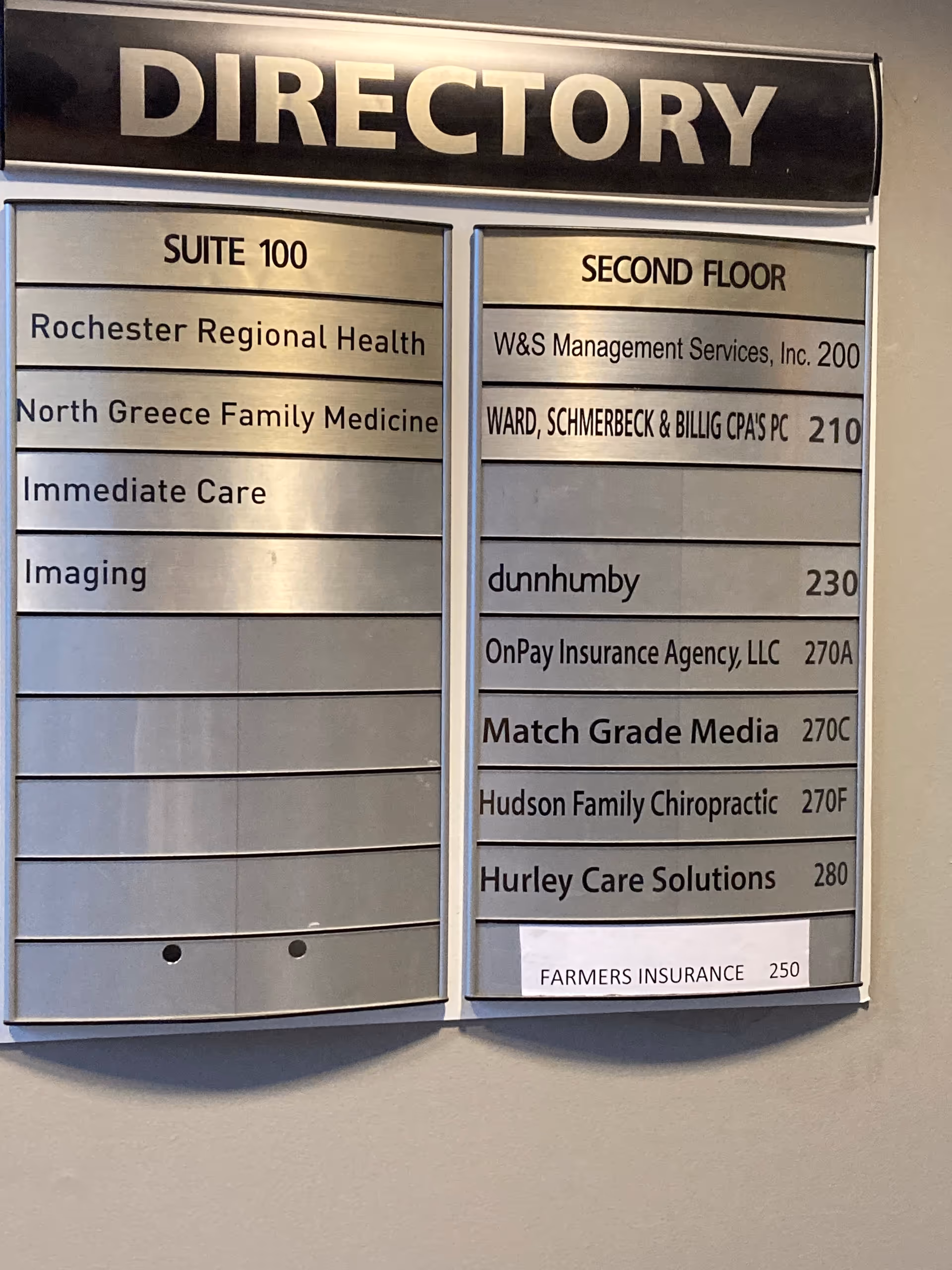 Wall-mounted directory sign listing suites and second-floor tenants.