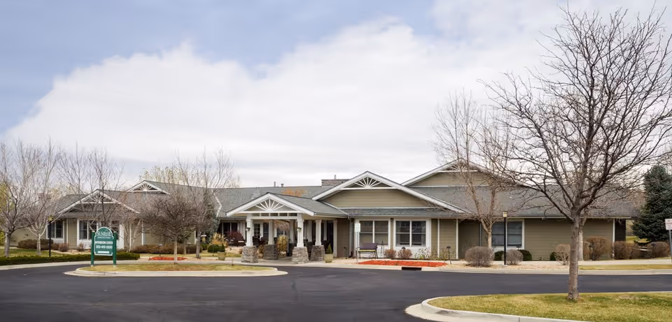 Front view of Sunrise Westminster senior living facility with entrance and leafless trees.