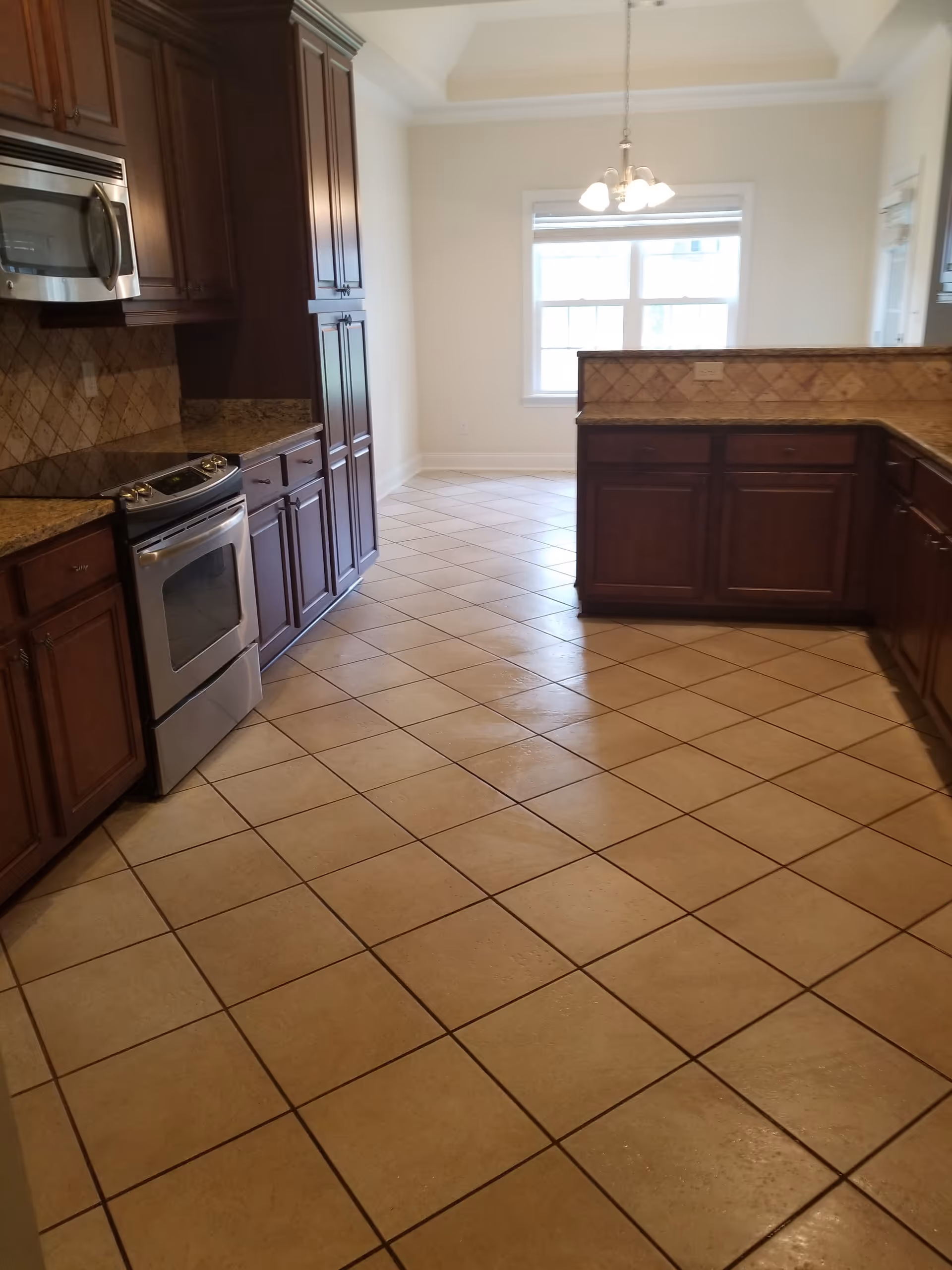 Spacious kitchen with granite countertops, dark wood cabinets, and tiled floor.