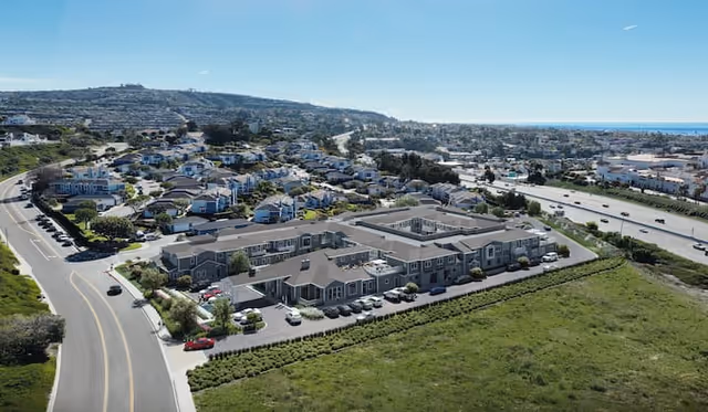 Aerial view of The Seville of San Clemente senior living complex with multiple buildings and parking.