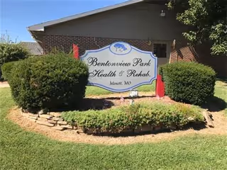 Exterior view of Bentonview Park Health & Rehab sign with trimmed shrubs.