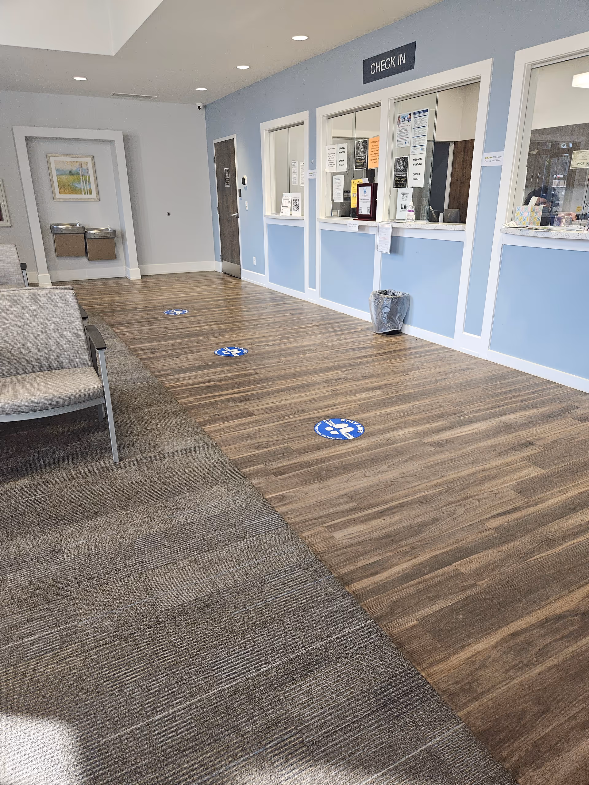 Lobby area with check-in windows, blue walls, and social distancing floor markers.