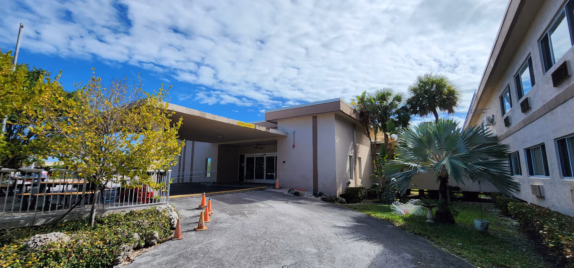Exterior view of Palm Vista Nursing and Rehabilitation Center entrance with palm trees and parked cones.