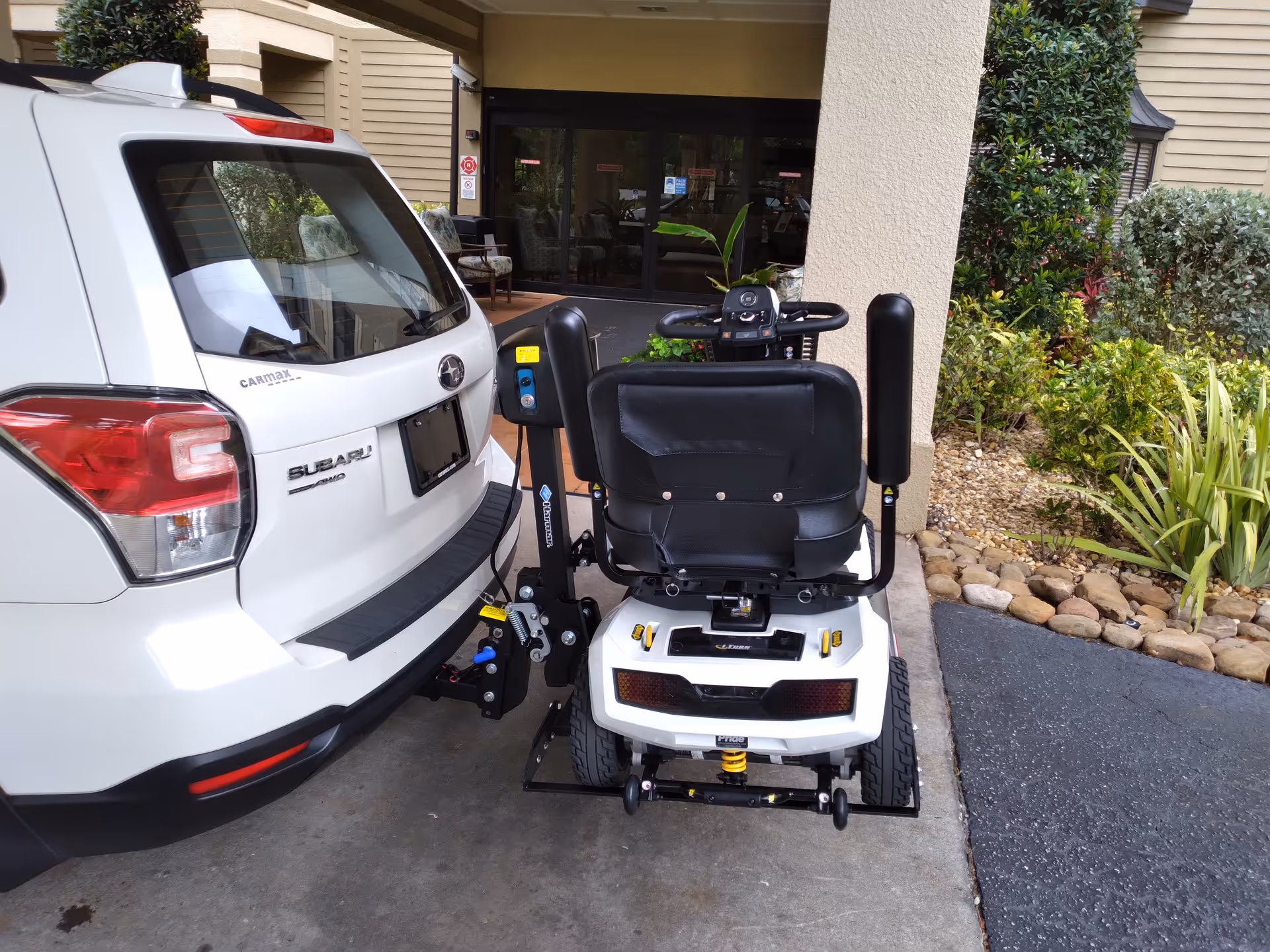 Mobility scooter parked outside the facility entrance beside a white SUV.