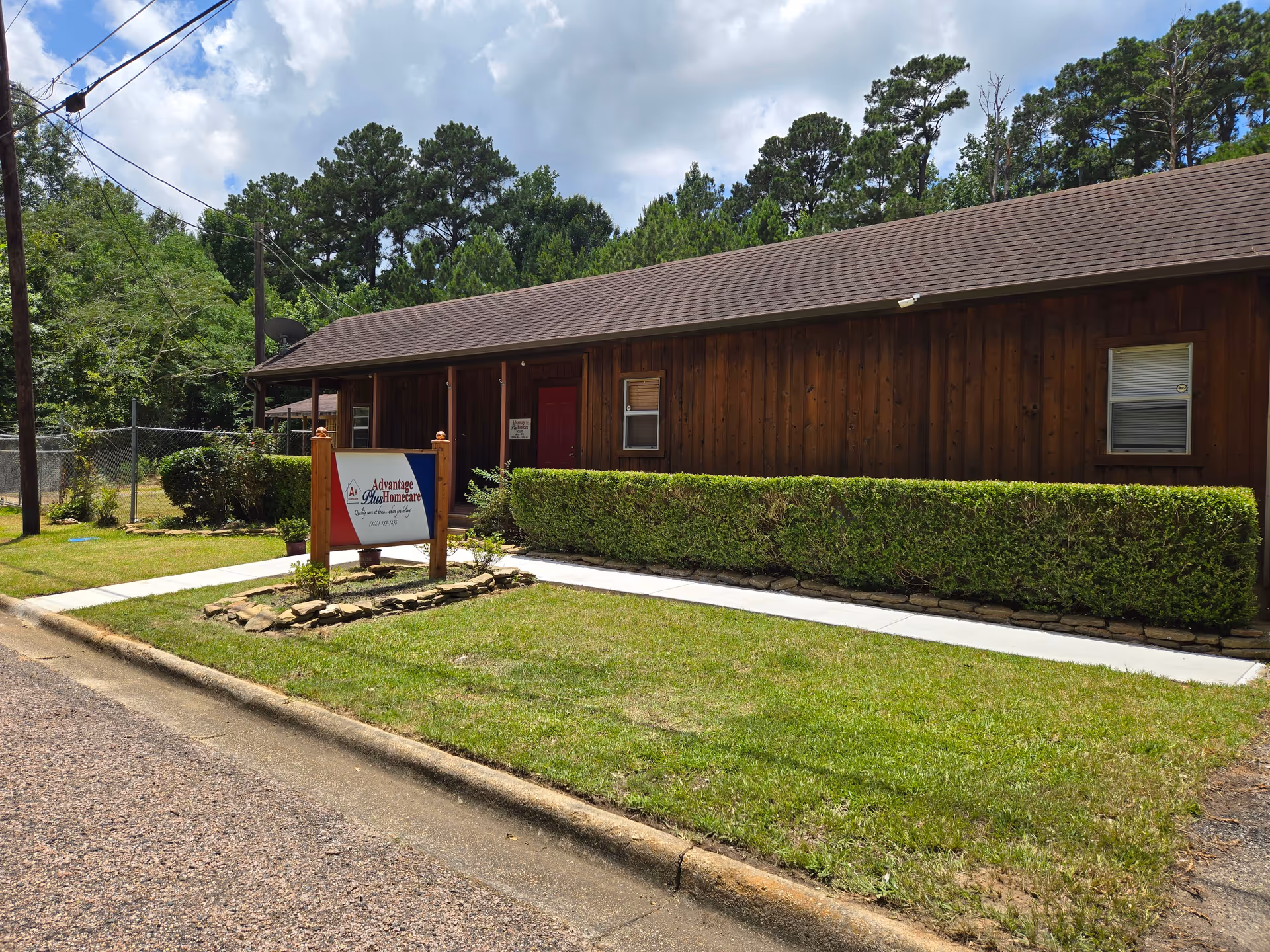 Exterior view of Advantage Plus Homecare building with sign and hedge.