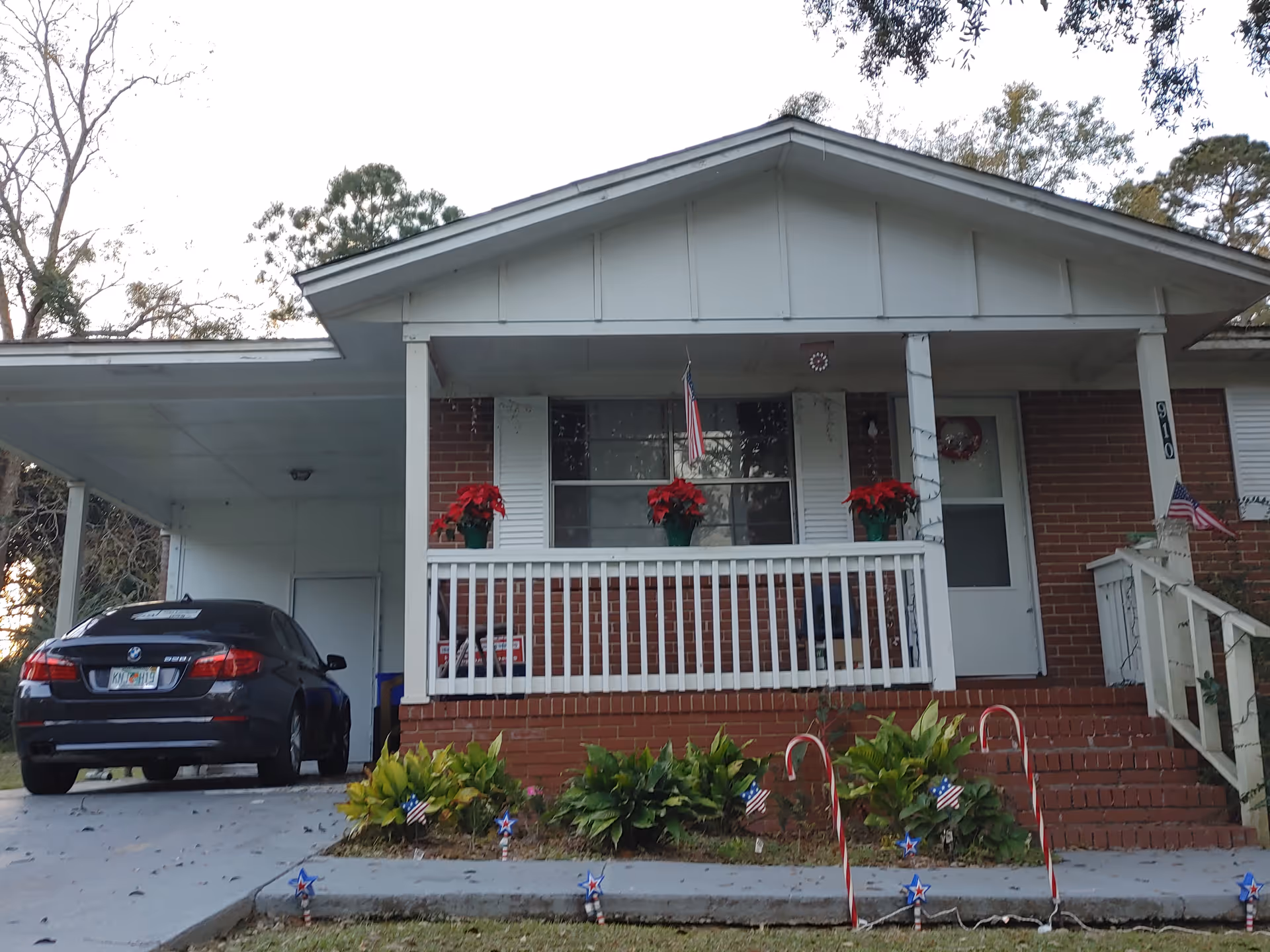 Front view of a brick senior living house with a porch and patriotic decorations.